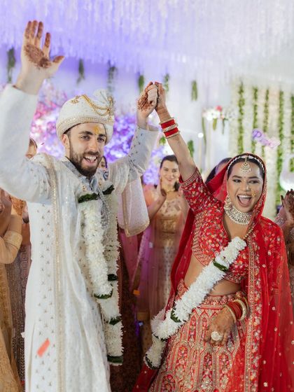 The moment of "I do!" This candid shot captures the couple's ecstatic celebration right after the ceremony, their hands raised in triumph and joy. A perfect end to the wedding rituals.