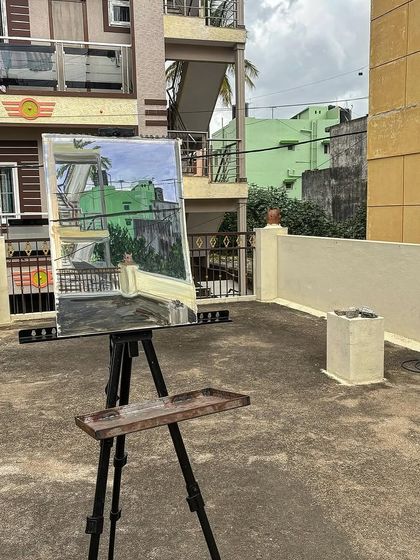 The finished acrylic painting of a green building, seen from a rooftop, perfectly matching the real-life view.