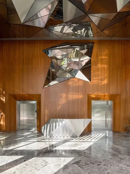 A central view of the directors' reception, where a sculptural steel desk and a dramatic ceiling installation create a powerful statement in a space defined by wood and marble.