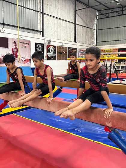 Young boys practice their L-sit on the balance beam. This strength hold is a great conditioning exercise for any apparatus.