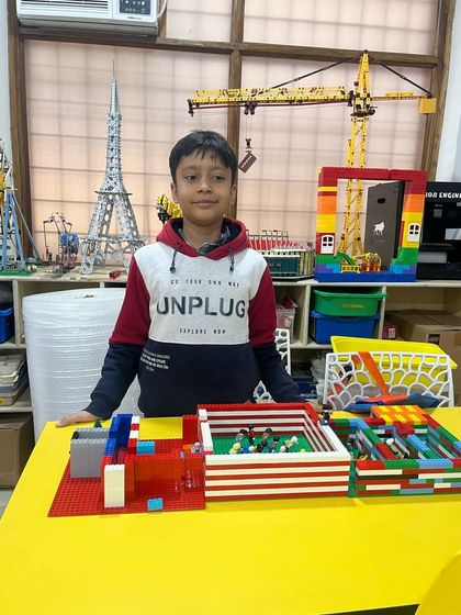 Another student in our workshop presents his LEGO creation, a structure that looks like a sports field or arena, showing his creativity and building skills.