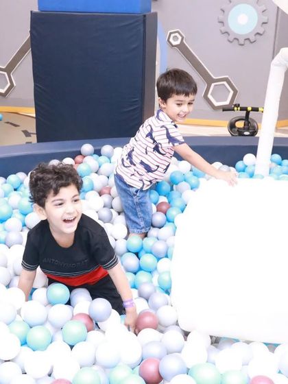 Two boys having a fantastic time in the ball pit. The area is designed to encourage cooperative play and shared excitement.