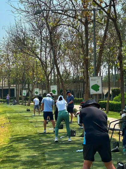 A view from behind a line of golfers, all in various stages of their swing.