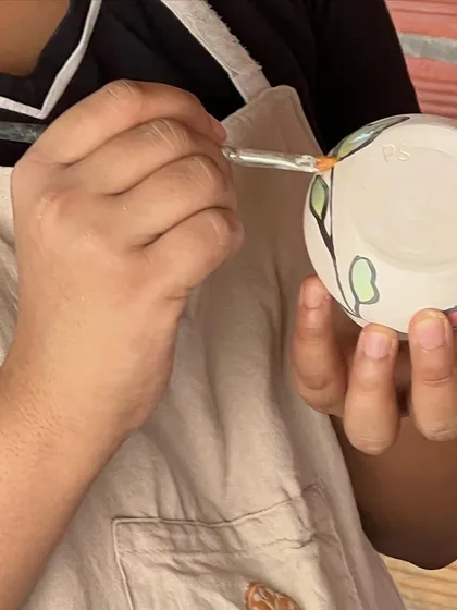 A student carefully applying underglaze to their pottery. This is where they add color and personality to their creations.
