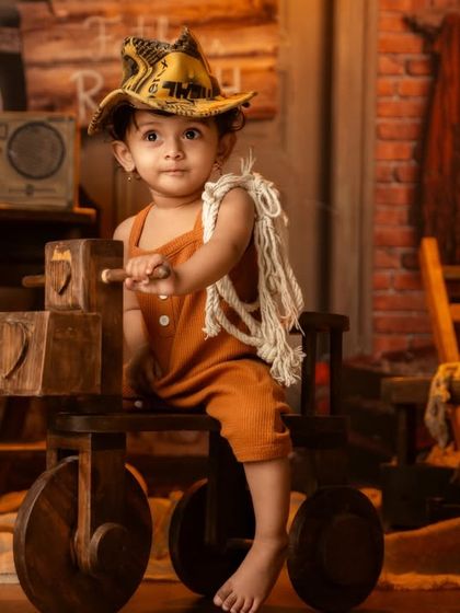 A little cowboy on his wooden horse, looking ready for an adventure on the ranch with a rustic, warm-toned setup.