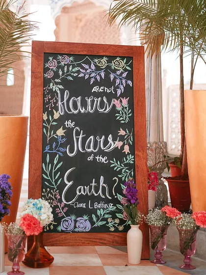 A charming welcome sign hand-drawn on a chalkboard, surrounded by flowers. This adds a personal and artistic touch to the event entrance.