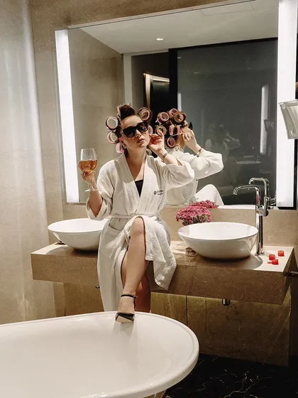 A cinematic portrait in a luxurious bathroom setting. The model's pose and the rich, warm lighting create a scene that feels like a still from a movie.