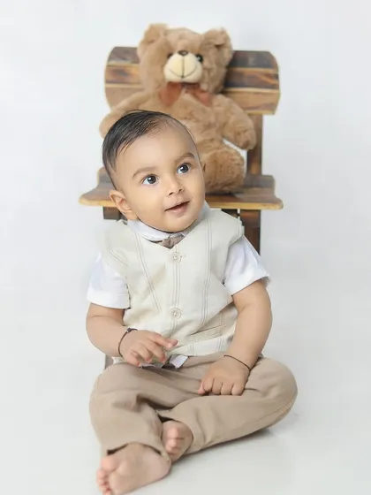 Looking up with a sweet, curious expression. The simple, neutral outfit is perfect for this classic style of portrait.