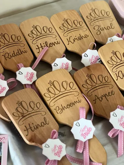 A whole set of personalized wooden hairbrushes, ready to be packed into bridesmaid hampers. Each one is engraved with a name and a little crown, because every girl in the squad is a queen.