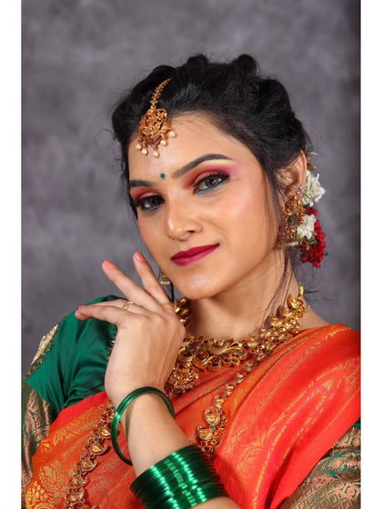 A classic three-quarter portrait in the studio, showcasing the vibrant colors of the saree and the intricate gold jewelry.