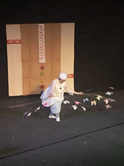 A wide shot showing the simple elegance of the 'Puppet Fantasy' stage, where the performer's dance and the puppets are the main focus.