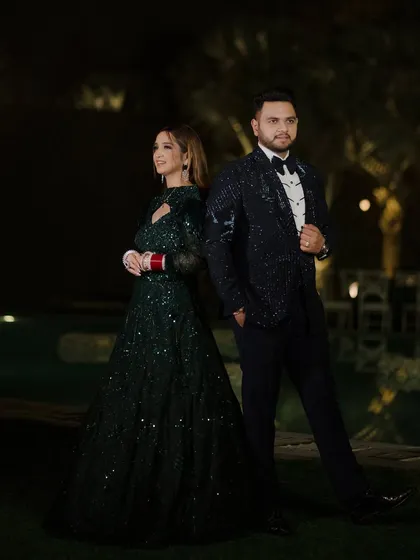 A stylish portrait of the couple at their outdoor reception. Dressed in glamorous evening wear, they pose back-to-back, exuding confidence and elegance.