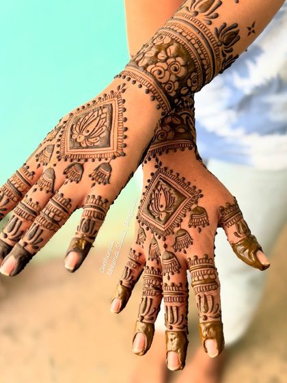 A stylish engagement mehendi with a diamond-shaped lotus motif and jhumka (dangling earring) patterns.