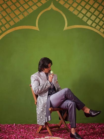 A relaxed, seated pose in the grey Indo-Western outfit. This image shows the versatility and comfort of the ensemble, suitable for long hours of celebration.