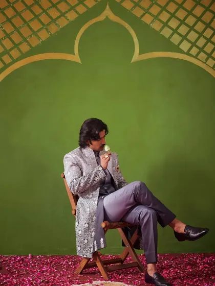 A relaxed, seated pose in the grey Indo-Western outfit. This image shows the versatility and comfort of the ensemble, suitable for long hours of celebration.