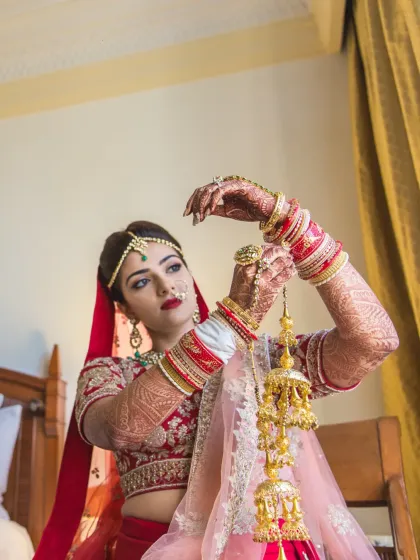 A close-up of the bride adjusting her kaleeras, a traditional and significant moment captured with beautiful detail.
