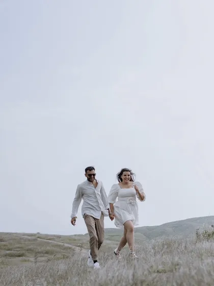 A candid shot of the couple walking hand-in-hand down a hill, capturing a natural and carefree moment during their pre-wedding shoot.