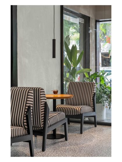 This cozy corner with bold, striped armchairs is perfect for quiet conversations. The minimalist pendant light provides focused illumination without distracting from the view of the greenery outside.