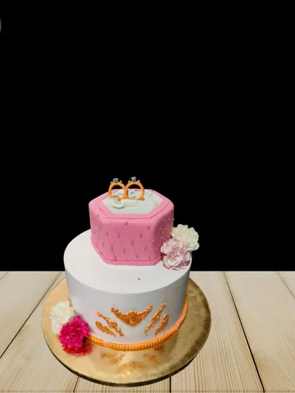 A simple yet elegant two-tier engagement cake. The top tier is a quilted pink ring box, while the bottom tier features delicate gold detailing, perfect for an intimate celebration.