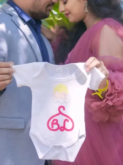 A close-up shot focusing on a baby onesie held by the expecting parents. This is a creative and personal way to announce your pregnancy during an outdoor shoot.