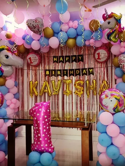 A first birthday party with a "Baby Girl" unicorn theme. This dense balloon arrangement in pink and blue features multiple unicorn head foil balloons and a personalized name banner for "KAVISHA".