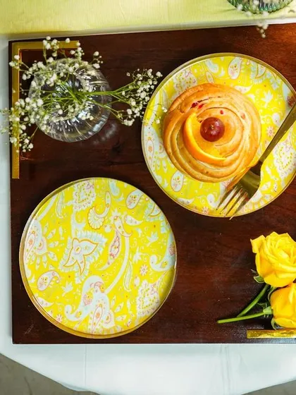 An overhead shot of a breakfast tray with patterned plates, a pastry, and a glass, perfect for hospitality marketing.