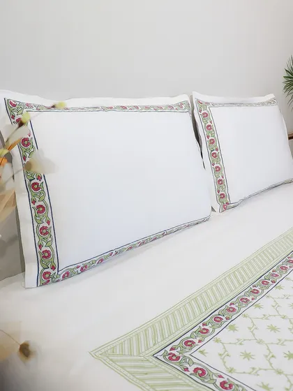 The pillowcases from our white bedding set, highlighting the intricate floral block-printed border. This timeless design brings a touch of garden-inspired elegance into the bedroom.