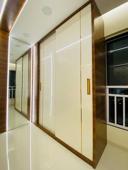 The completed sliding wardrobe with high-gloss laminate and dark wood finish. The sleek design and integrated lighting make it a stunning addition to the bedroom.