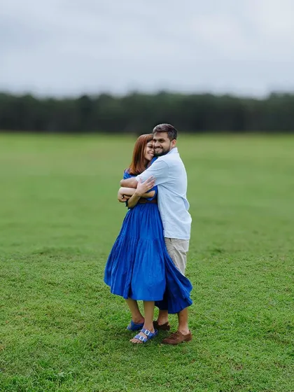An embrace in the middle of a wide, green field. This wide shot emphasizes the couple against the vastness of nature, creating a feeling of peaceful solitude and connection.