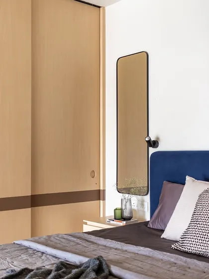 The bedroom features a sliding wardrobe in a light wood finish, with a contrasting dark band. The simple, clean lines are a hallmark of the Wabi-Sabi aesthetic.