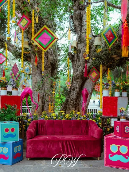 A quirky and colorful photo booth for a Mehendi, with a pink velvet sofa, funky props, and vibrant hangings.