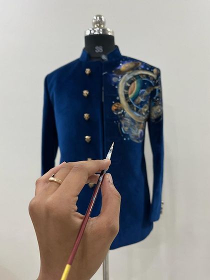 Adding the final, delicate details to the universe-themed velvet sherwani. A tiny brush is needed for such intricate work.