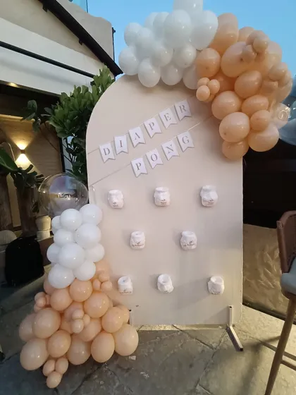 Fun and games for a baby shower. This "Diaper Pong" game board is a creative and interactive element we can add to your celebration, decorated with a matching balloon garland to keep everything on-theme.