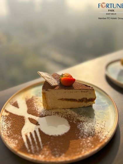 Our classic Tiramisu, served on a rustic plate with a creative fork-and-spoon stencil made from cocoa powder.