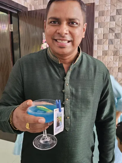 A guest enjoying a vibrant blue cocktail, complete with a personalized photo tag of the couple. These small details make a big impression.
