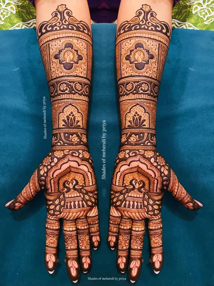 A stunning example of symmetrical bridal mehendi. Both hands feature identical patterns of peacocks, lotuses, and traditional Indian architecture.