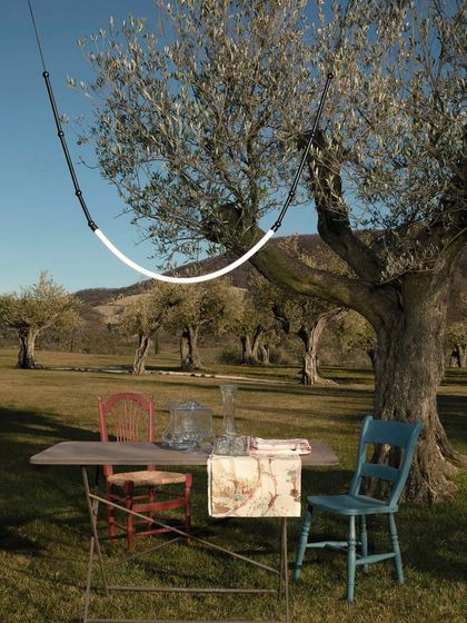 The Leda light creates a magical outdoor dining experience, suspended between trees in a beautiful, open field.
