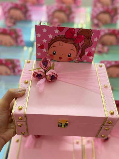 Sweet return favours for a baby girl's naming ceremony. These mini trunk boxes in pastel pink and blue are decorated with cute cartoon cards and floral details.