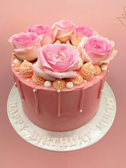 A lovely pink drip cake for a mother's birthday, topped with fresh pink roses. This design is a beautiful and heartfelt way to show your love.