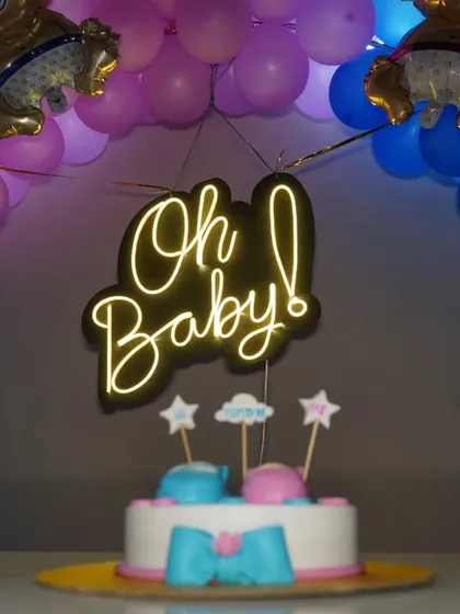 A wide shot of the baby shower cake table with a blue and purple balloon arch. This photo captures the full decorative setup.