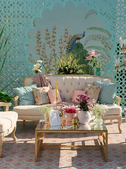A beautiful pastel-themed seating area with a custom-painted peacock backdrop. The soft blue and pink tones in the decor create a calm and dreamy atmosphere, perfect for a daytime event.