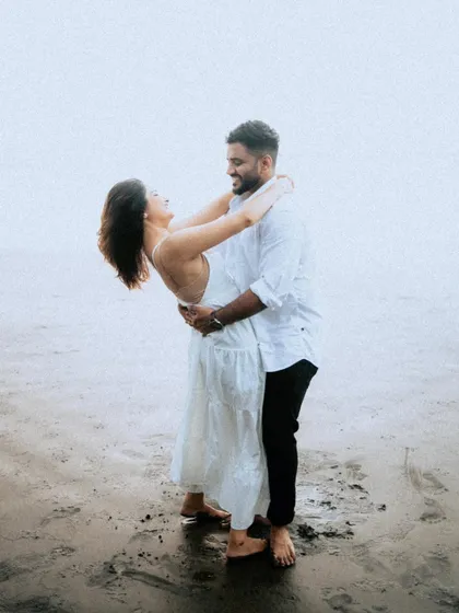 A romantic and playful dip on the beach. This pose is full of laughter and connection, showing a couple completely lost in their own world.