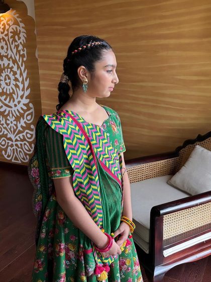 A side profile of the young client, showing the crown braid and the long, thick braid down her back.