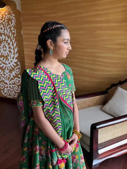 A side profile of the young client, showing the crown braid and the long, thick braid down her back.