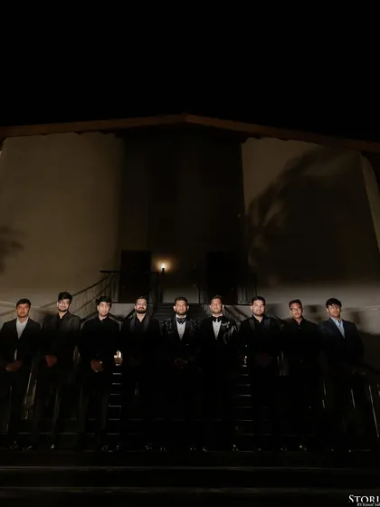 A moody, dramatic group portrait of the groom and his groomsmen, lined up on a staircase at night.