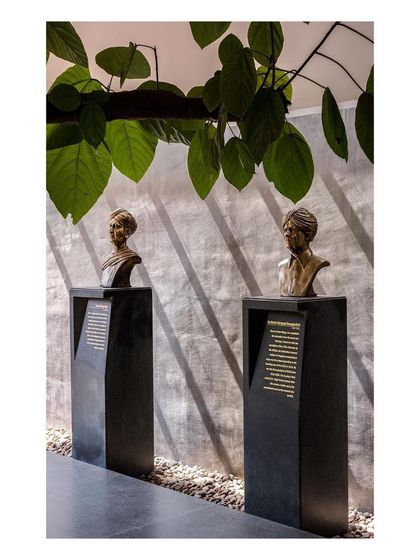 A close-up of the bronze busts on their black granite pedestals. The play of light and shadow on the concrete wall behind adds texture and depth to the display.