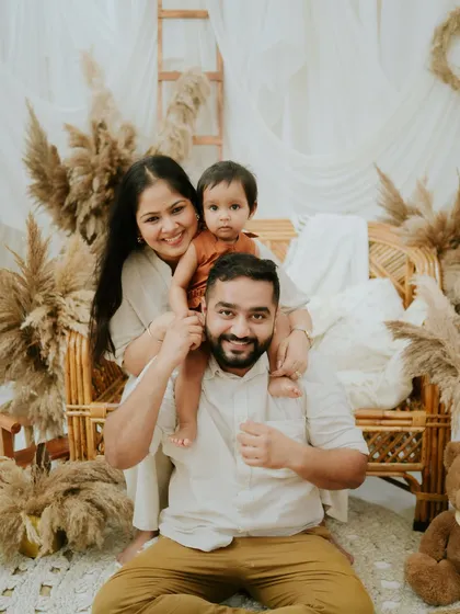 A fun and playful family pose. Having their daughter on her dad's shoulders adds a dynamic and joyful element to the photo.