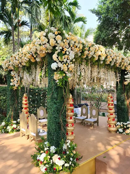 A side view of the green and cream floral mandap, showing how the structure integrates with the natural surroundings for a seamless and beautiful outdoor wedding.