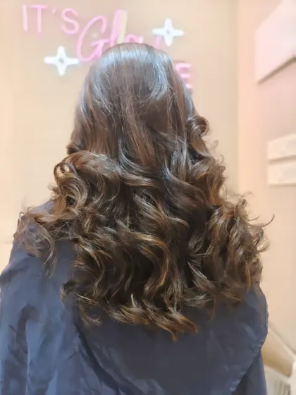 The back view of a gorgeous head of highlighted curls. The light catches the different tones, creating a rich and dimensional effect.