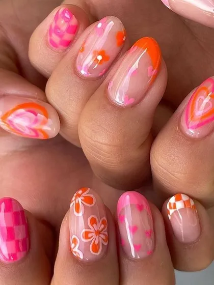 Why choose one design when you can have them all? This playful and creative manicure features a different design on each nail, including checkerboard patterns, florals, swirls, and hearts in a vibrant pink and orange color scheme.